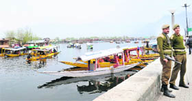 Security forces personnel stand guard as tourists enjoy a ride aboard a shikara on the Dal Lake in Srinagar on Friday.
