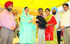 Bathinda MP Harsimrat Kaur Badal giving a laptop to a student of the Punjab Institute of Technology, Nandgarh, during a function organised at the PTU GZS campus in Bathinda on Friday.