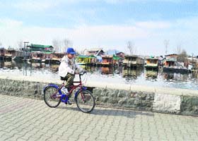 A cyclist rides on the banks of the Dal Lake in Srinagar