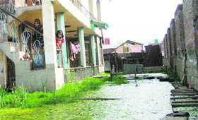 Family members look at stagnant water in front of their house at Bemina Hamadana Colony on the outskirts of Srinagar on Sunday.