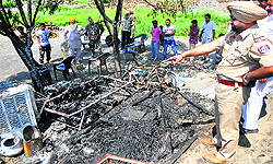 A policeman points towards the charred remains of a shanty that caught fire in Ludhiana on Sunday