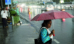 A woman waits for a bus during the downpour in New Delhi in the evening on Tuesday