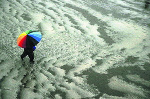 A woman walks with an umbrella during a heavy hailstorm in Shimla.