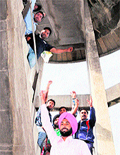 Youngsters demanding jobs in power corporation on compassionate grounds protest at a water tank in Pink Plaza, Amritsar, on Wednesday