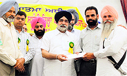 Education Minister Sikandar Singh Maluka hands over a cheque for subsidy on farm equipment to a farmer 