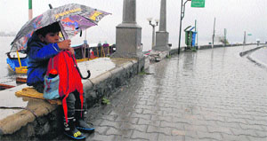 A boy awaits his school bus on the banks of the Dal Lake on a wet Wednesday morning in Srinagar. 