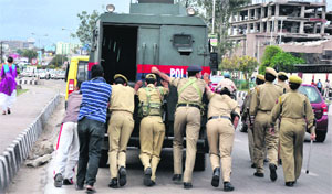 Policemen push an old bullet-proof security vehicle on a busy road in Jammu on Wednesday. The vehicle was deployed at Kala Kendra in view of the visit of Governor NN Vohra.
