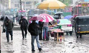 Pedestrians walk through a wet road in Srinagar on Wednesday.