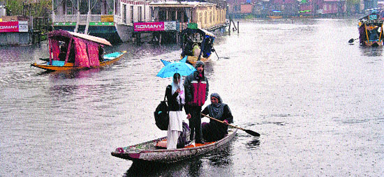 A woman ferries people in a boat on the Dal Lake in Srinagar on Wednesday. 