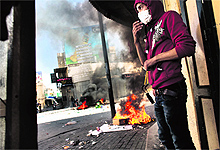 A Palestinian demonstrator protects himself from tear gas in the West Bank city of Hebron on Tuesday