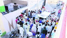 Policemen and residents outside the house where a woman was found murdered, at Guru Ki Nagri in Bathinda on Thursday