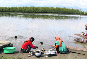 Women wash utensils on the banks of Wular Lake in Bandipora on Thursday.