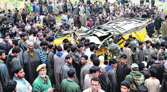 Police personnel and villagers gather around the ill-fated school bus which met with an accident at Mohiripora village in Anantnag on Thursday.