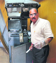 A bank official inspects a damaged ATM in Ludhiana on Sunday. 