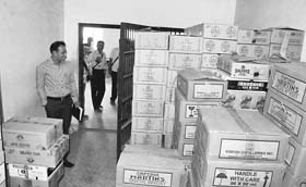 Officials inspect the cases of liquor bottles seized on Sunday in Chikmagalur during high vigil owing to upcoming Assembly elections in the state