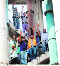 Protest continues: Unemployed youths atop a water tank at a market in Amritsar on Monday.