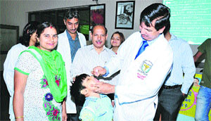 RC Siwach, Director of BPS Government Women Medical College, Khanpur Kalan, administers polio drops to a child during a special camp on the college premises.