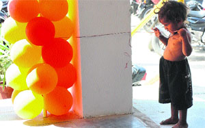 A child tries to play with balloons at a gate near a shop in Karnal.