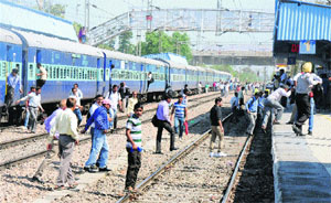 Unaware of the risk involved, people cross a railway track to reach platforms at Karnal railway station. 