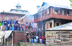 Residents try to douse a fire that engulfed a house in the Chatabal area of Srinagar on Monday. Tribune photo: Yawar Kabli