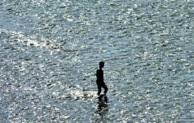 A man crosses the Tawi river near Sher-e-Kashmir Bridge in Jammu on Tuesday.