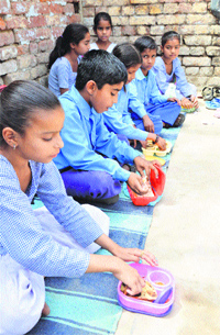 Students of Government Primary School, Field Ganj, Ludhiana, eat lunch from their own tiffin boxes on Tuesday.