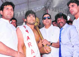 Suresh Sharma (in spectacles), IG, Punjab Police, gives cash prize and a mace to Joginder for winning a wrestling bout at Panchi Jatan village in Sonepat recently