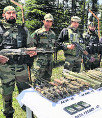 Army soldiers display a huge cache of arms and ammunition recovered by them from Rajwar forests in Handwara on Wednesday