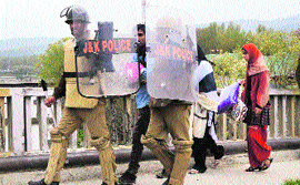 Policemen escort a newborn and his parents to safety amid stone-pelting in Baramulla on Thursday.