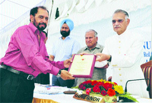 Ludhiana-based ophthalmologist Rajinder Singh receives an award from the Governor of Punjab and the President of the Punjab State Red Cross Branch at the Punjab Raj Bhawan in Chandigarh on Thursday. 