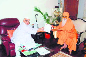 Mahant Ramsharan Giriji  of Juna Akhara presents a memorandum to Governor Aziz Qureshi in Dehradun on Friday. 