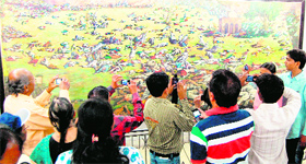 Visitors click photographs of a painting describing the historical scene of the massacre of Jallianwala Bagh on the occasion of the 94th anniversary of the event.