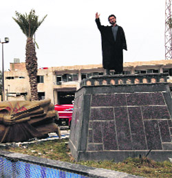 A man raises his hand as he stands on the spot where the statue of President Bashar Al-Assads father used to be in eastern Syria. 