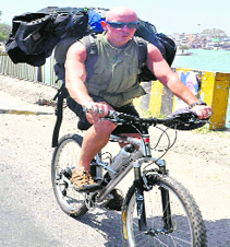 A foreigner rides a bicycle adjacent to the Ganga canal to enjoy the view in Haridwar. 
