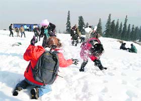 Cool comfort: Tourists play with snow at the ski resort of Gulmarg in north Kashmir on Sunday