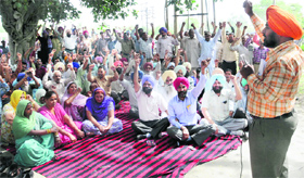 Members of the Sangharsh Committee of Guru Nanak Dev Thermal Plant (GNDTP) hold dharna against the PSPCL management outside the power plant in Bathinda on Tuesday.
