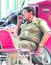 A police official smokes on the premises of the Patiala temple at the Mansa Devi shrine on Tuesday.