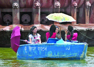 Girls hold umbrellas to save themselves from the scorching heat even as they enjoy boating at India Gate in New Delhi on Tuesday. The maximum temperature in the city was recorded 40 degree Celsius.
