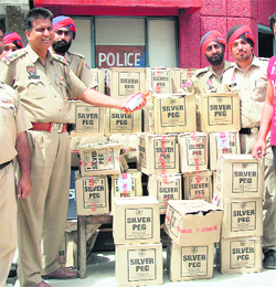 The police with the liquor boxes seized from a house in Ekta Nagar.