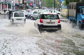 Vehicles wade through a waterlogged road in Srinagar on Tuesday