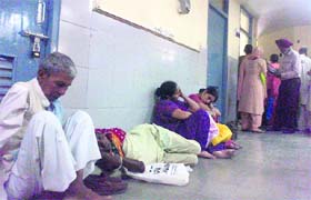 Jai Singh sits on the floor as he could not find an empty chair outside the chest clinic. His wife lies by his side