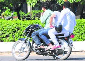 Students ride a two-wheeler without helmets on the PU campus in Chandigarh on Wednesday