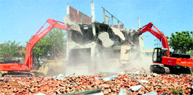 A machine pulls down a structure at Kishengarh village in Chandigarh on Thursday.