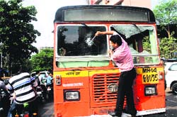 A protester vandalises a bus during a bandh in Thane, Mumbai, on Thursday.  PTI