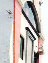 A worker cleans a high-rise building without necessary equipment on the GT Road in Amritsar.