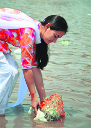 A devotee immerses Saankh (barley sprouts) in Tawi River on the occasion of Ram Navami