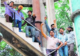 Youths protest atop a water tank in Amritsar on Saturday