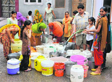 People rush to get their daily supply of water as a water tanker of the Municipal Corporation arrives in their locality behind the main bus stand in Bathinda on Saturday