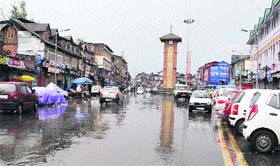 Rain brings chill: The clock tower at Lal Chowk in Srinagar is reflected in the rain-drenched street on Saturday