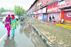 Residents walk with an umbrella as showers lashed Srinagar on Saturday.